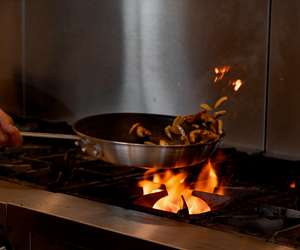 chef sauteeing food over a flame